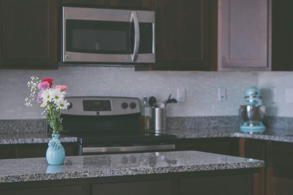 A contemporary kitchen featuring granite countertops and a vase of colorful flowers, creating a warm ambiance.
